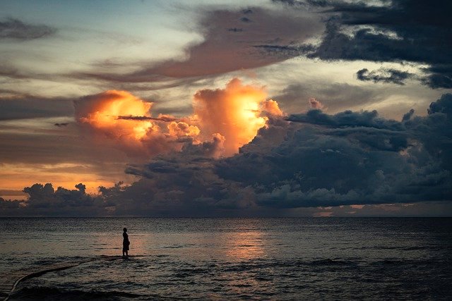 silhouette-dans-paysage-plage-mer-ciel-nuageux-soleil-couchant