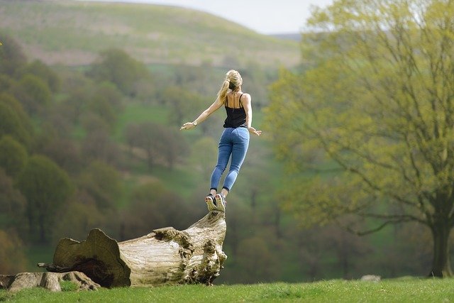 Femme-de-dos-en-equilibre-sur-tronc-arbre-dans-nature